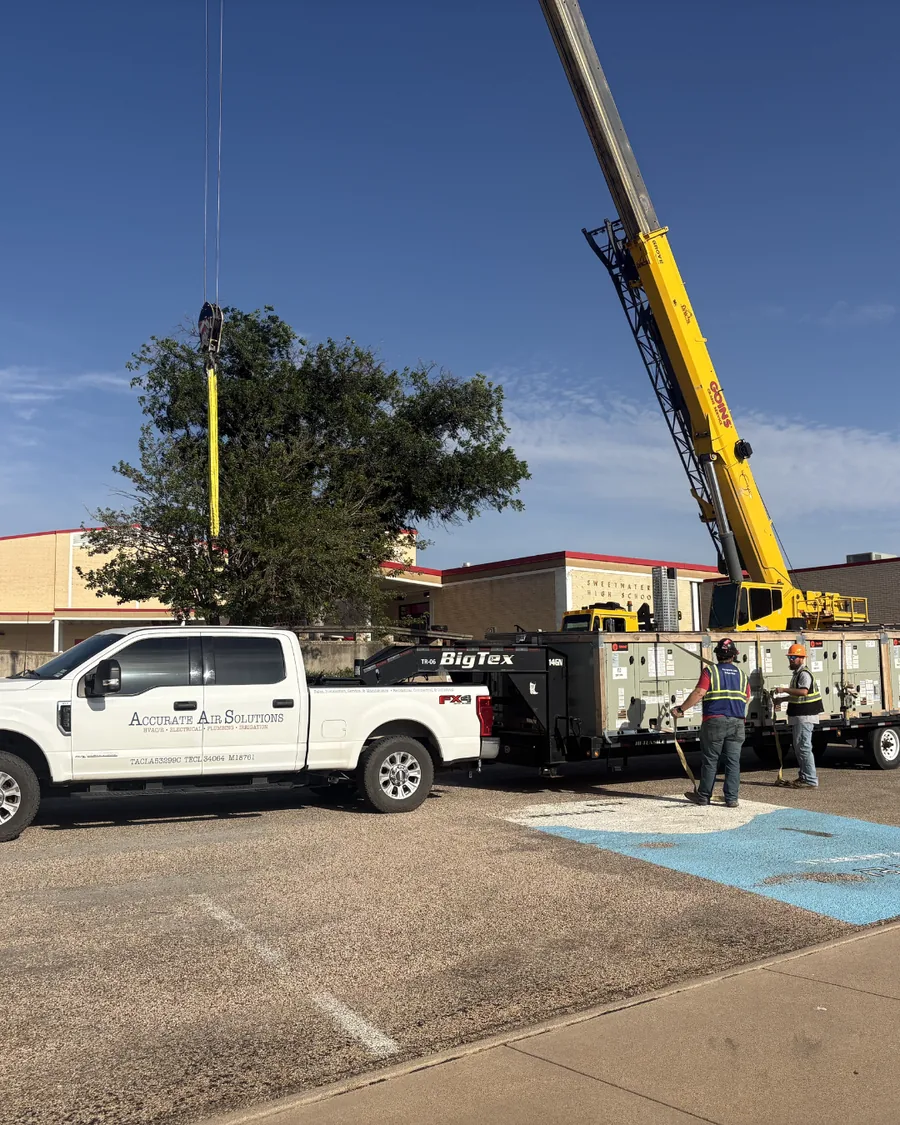 Crane setting rooftop units on a commercial building