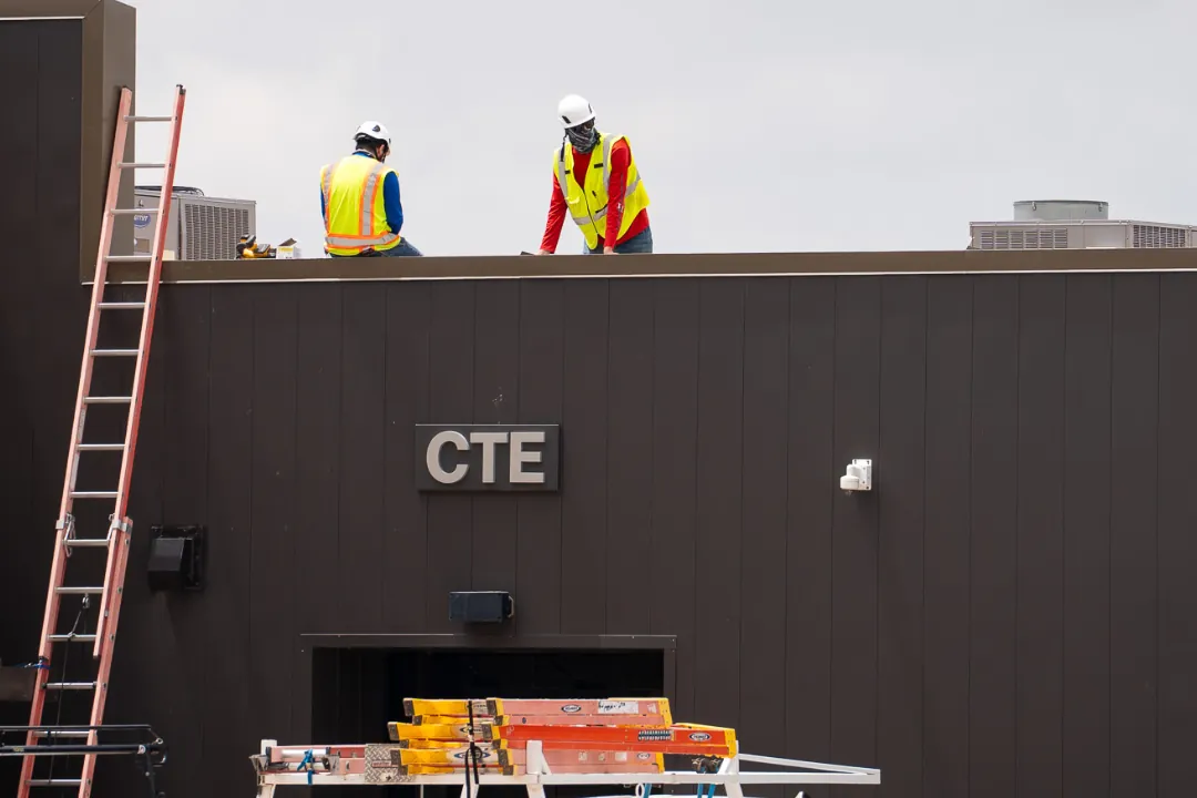 Crew working a commercial roof with service trucks staged below